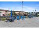 View of the community pool deck with chairs and tables with building facade and parking beyond the fence at 25100 Sandhill Blvd # R201, Punta Gorda, FL 33983
