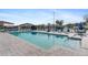A view of the community pool, surrounded by a stone paver deck with lounge chairs and sun umbrellas at 25100 Sandhill Blvd # R201, Punta Gorda, FL 33983