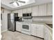 Well-lit kitchen with white cabinets, stainless steel refrigerator, and modern appliances at 26461 Explorer Rd # F, Punta Gorda, FL 33983