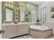 Green-walled bathroom with a soaking tub, double vanity, decorative mirrors, and ample natural light at 303 11Th E Ave, Palmetto, FL 34221