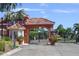 Gated entrance with tiled roof, lush landscaping, and visitor access at 303 11Th E Ave, Palmetto, FL 34221