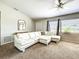 Bright living room featuring a large white sectional sofa, neutral carpet, and natural light from the windows at 4097 Rose Arbor Cir, Port Charlotte, FL 33948