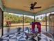 View of backyard and mature landscaping from a screened patio with checkerboard floor and hanging swing chair at 4097 Rose Arbor Cir, Port Charlotte, FL 33948