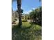 The landscaped backyard has grass with palm trees, bushes, and other small buildings at 4344 Commercial St, Port Charlotte, FL 33953