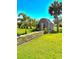 A lush yard with a storage shed featuring a small window and surrounded by vibrant greenery at 4344 Commercial St, Port Charlotte, FL 33953