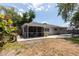 Home's backyard showcasing the screened patio, lush trees, and well-maintained landscaping at 5333 Simrak St, North Port, FL 34287