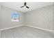 Spacious bedroom featuring a modern ceiling fan, stylish accent wall, and light gray flooring at 6245 Alhambra Ave, North Port, FL 34291
