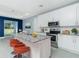 Modern kitchen featuring stainless steel appliances, granite countertops, and stylish orange barstools at 6245 Alhambra Ave, North Port, FL 34291