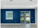 Bright living room featuring sliding glass doors, modern gray floors, and a striking blue accent wall at 6245 Alhambra Ave, North Port, FL 34291