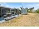 An open backyard featuring a storage shed, grill, and a screened porch area with pool access and green surroundings at 6531 Marius Rd, North Port, FL 34287