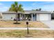 Charming single-story home with a well-manicured lawn, a light blue door, and an attached garage at 6531 Marius Rd, North Port, FL 34287