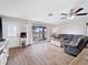 Cozy living room with wood-look floors, a ceiling fan, and a large window providing ample natural light at 6531 Marius Rd, North Port, FL 34287
