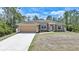 Charming one-story home with a well-manicured lawn and a two-car garage, nestled among tall pine trees at 7135 Tropicaire Blvd, North Port, FL 34291