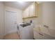 Well-lit laundry room with washer, dryer, utility sink, and convenient overhead cabinets at 7135 Tropicaire Blvd, North Port, FL 34291