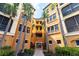 Multi-story condo complex with tan and yellow exterior, a brick pathway, and tropical landscaping at 99 Vivante Blvd # 311, Punta Gorda, FL 33950
