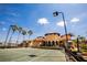 Well-maintained tennis court and clubhouse with yellow accents, surrounded by palm trees and blue sky at 99 Vivante Blvd # 311, Punta Gorda, FL 33950