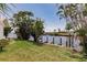 Backyard view of a waterfront canal home with dock, tropical landscaping, and seawall at 12439 Prather Ave, Port Charlotte, FL 33981