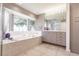 Bathroom featuring a tub, shower and a large window overlooking the lush landscaping at 12439 Prather Ave, Port Charlotte, FL 33981