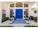 Welcoming front entrance with a bright blue door, potted flowers, and stylish outdoor seating at 12439 Prather Ave, Port Charlotte, FL 33981
