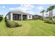 Spacious backyard showcasing a screened lanai, lush lawn, and palm trees at 15830 Appalachian Dr, Punta Gorda, FL 33982