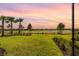 Beautiful backyard view overlooking a manicured lawn, pond, and sunset at 15830 Appalachian Dr, Punta Gorda, FL 33982
