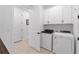Bright laundry room featuring white cabinetry, modern washer and dryer, and neutral tile flooring at 15830 Appalachian Dr, Punta Gorda, FL 33982