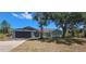 Charming single-story home featuring a two-car garage, light green exterior and mature trees in the front yard at 17356 Gulfspray Cir, Port Charlotte, FL 33948