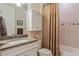 Well-lit bathroom features a vanity with a solid surface countertop and a shower with a decorative curtain at 1745 Hyssop Loop, North Port, FL 34289