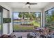 Enclosed patio features a scenic view of a lake with a table, chairs, and tropical decor at 1745 Hyssop Loop, North Port, FL 34289