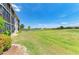 Scenic view from a screened-in lanai, overlooking a spacious lawn and community pond at 175 Kings Hwy # 1114, Punta Gorda, FL 33983