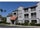 Condo building with screened balconies, red tile roof, gray facade, and parking in the foreground at 18001 Richmond Place Dr # 636, Tampa, FL 33647
