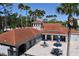 Overhead view of clubhouse with red tile roof, tables with umbrellas, and well-maintained grounds at 18001 Richmond Place Dr # 636, Tampa, FL 33647