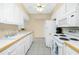 Well-lit kitchen featuring white appliances, white cabinets, and a view into the dining area at 22375 Edgewater Dr # 128, Port Charlotte, FL 33980