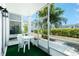 Enclosed screened porch area with table and chairs and a view of the manicured yard at 22375 Edgewater Dr # 128, Port Charlotte, FL 33980