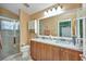 Bathroom featuring wood cabinets, double sinks, and a glass-enclosed shower at 24317 Kintail Ct, Punta Gorda, FL 33980