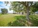 View of the backyard featuring lush grass, mature trees, and the back of a beige two story home at 26100 Paysandu Dr, Punta Gorda, FL 33983