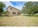 Large backyard featuring lush grass, mature trees and a beige two story home at 26100 Paysandu Dr, Punta Gorda, FL 33983