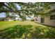 Backyard featuring lush grass, mature trees, and the back of a beige two story home at 26100 Paysandu Dr, Punta Gorda, FL 33983