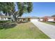 Inviting single-story home with a driveway, manicured lawn, and mature tree in a sunny neighborhood at 2751 S Cranberry Blvd, North Port, FL 34286