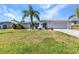 Charming single-story home with a lush green lawn, beautiful landscaping, and an attached garage at 318 Spring Lake Nw Blvd, Port Charlotte, FL 33952