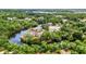 Wide aerial view shows a canal-front home featuring a screened lanai, trees, and a private dock at 3400 Allapatchee Dr, Punta Gorda, FL 33950