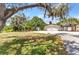 Charming home featuring a two-car garage, stone accents, and lush landscaping with mature trees and green grass at 3400 Allapatchee Dr, Punta Gorda, FL 33950