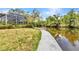 Waterfront view of home, concrete walkway leading to the canal, and lush landscaping and greenery at 3400 Allapatchee Dr, Punta Gorda, FL 33950