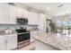 Bright kitchen features white cabinets, granite countertops, stainless steel appliances, and stylish backsplash at 43050 Greenway Blvd # 645, Punta Gorda, FL 33982