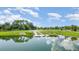 Picturesque pond with a floating dock and lush green surroundings under a bright blue sky with scattered clouds at 43050 Greenway Blvd # 645, Punta Gorda, FL 33982