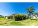Expansive backyard featuring a screened lanai, lush tropical landscaping, and green lawn at 4992 Brittain Way, North Port, FL 34287