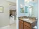 Bathroom featuring granite counters, wood cabinets, decorative mirror, and an interior kitchen view at 4992 Brittain Way, North Port, FL 34287