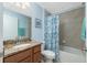 Bright bathroom featuring vanity with granite countertop and tiled shower behind a patterned curtain at 4992 Brittain Way, North Port, FL 34287
