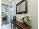 Inviting home entryway featuring a decorative table with a mirror, flowers, and natural light at 4992 Brittain Way, North Port, FL 34287