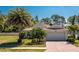 Charming single-story home featuring well-manicured lawn, palm trees, and a brick-paved driveway leading to a two-car garage at 4992 Brittain Way, North Port, FL 34287